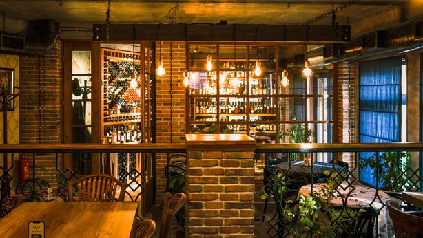A cozy restaurant with brick walls, wooden tables, and hanging light bulbs. - VinoOdor Wine Boutique Hotel in Telavi (Telavi)