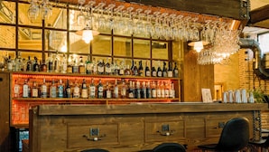 A bar area with shelves of liquor bottles, hanging wine glasses, and a wooden counter. - VinoOdor Wine Boutique Hotel in Telavi (Telavi)