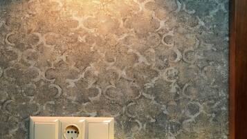 Una lámpara de pared con pantalla cilíndrica, un enchufe y una lámpara de mesa con estructura de vidrio.