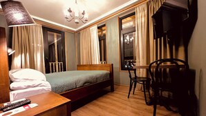 A hotel room with a bed, a desk with a chair, a TV, and a chandelier. - VinoOdor Wine Boutique Hotel in Telavi (Telavi)