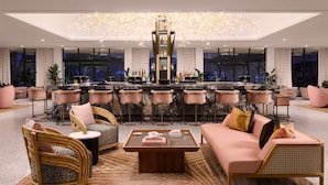 A modern lounge area with a bar, seating arrangements, and a large chandelier.