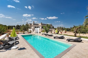 A swimming pool with lounge chairs and umbrellas, surrounded by a landscaped garden and a building in the background. - 3635 Villa Dolce - App 2 by Barbarhouse (Ostuni)