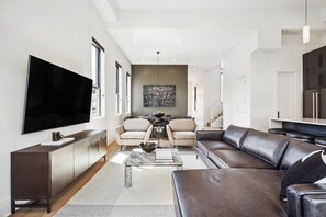 Una sala moderna con un televisor de pantalla plana grande, un sofá de cuero y una mesa de centro de mármol.