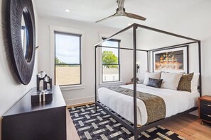 Un dormitorio moderno con cama con dosel, ventanas amplias y ventilador de techo.