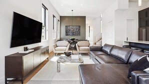 Een moderne woonkamer met een grote flatscreen-tv, een leren bank en een marmeren salontafel.