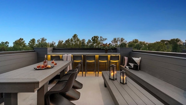 An outdoor patio with a dining table, chairs, and a bar area with stools.