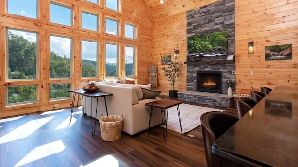 A spacious living room with large windows, a stone fireplace, and a cozy seating area. - Mountain Views/Near DwTn Gat/New (Gatlinburg)