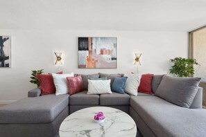 Un soggiorno moderno con un divano modulare grigio, un tavolino da caffè in marmo e opere d'arte astratte alle pareti.