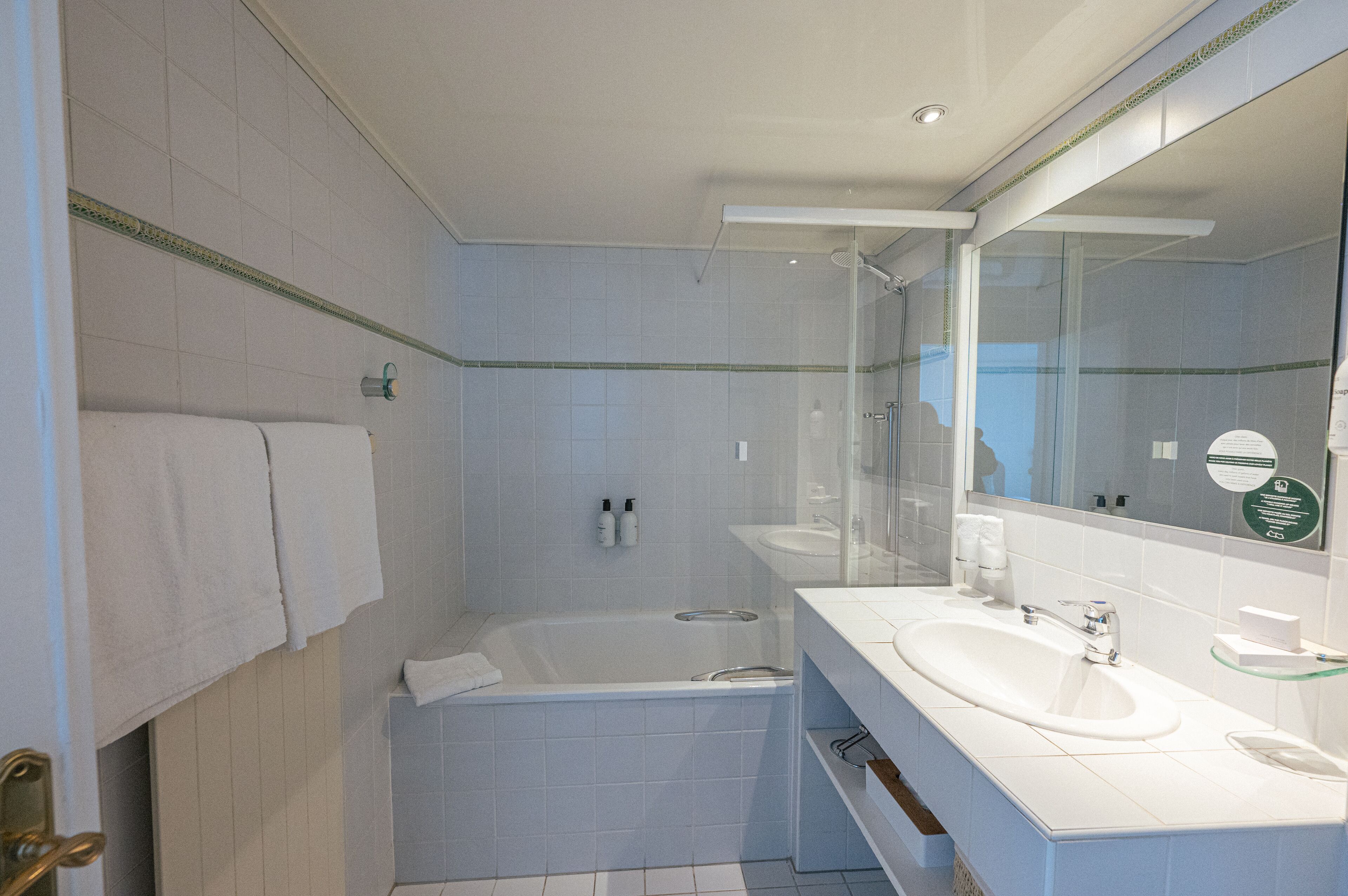 A modern bathroom with a bathtub, a large mirror, and a sink.