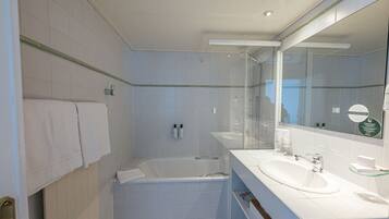 A modern bathroom with a bathtub, a large mirror, and a sink.