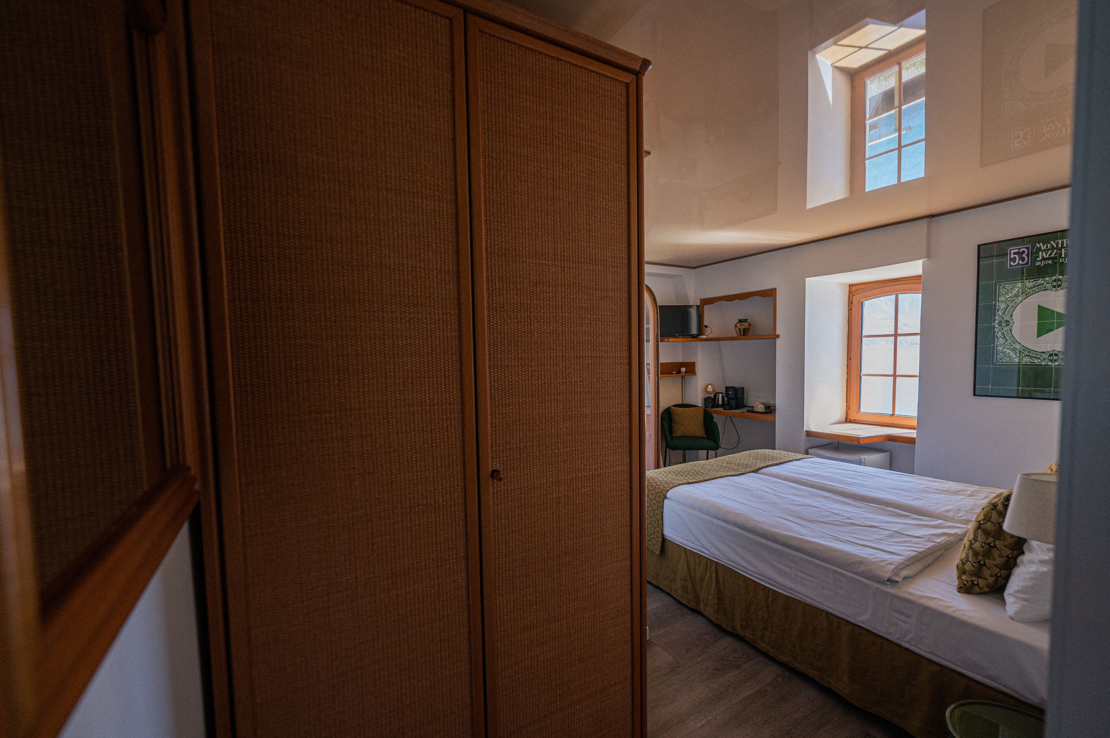A bedroom with a bed, a window, a desk, and a wardrobe.