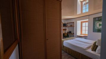 A bedroom with a bed, a window, a desk, and a wardrobe.