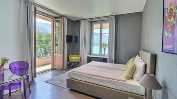 Un dormitorio moderno con una cama grande, televisor, una silla y vistas al exterior.