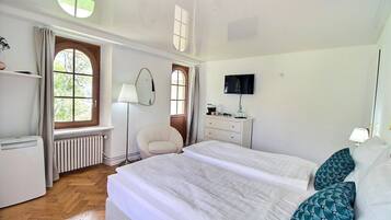 Une chambre à coucher avec un grand lit, une chaise, un bureau, une télévision et un radiateur.