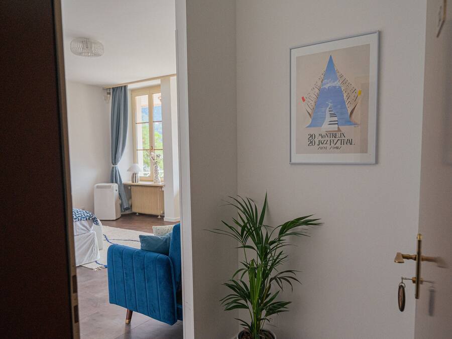 Une chambre d’hôtel avec un lit, une plante en pot et un tableau encadré accroché au mur.
