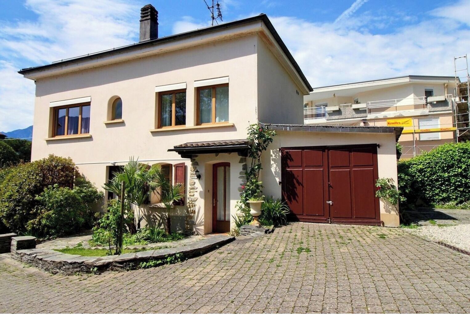 Ein zweistöckiges Haus mit Garage, einem kleinen Garten und einem gepflasterten Auffahrtsweg.