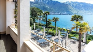 Un balcon avec coin salon extérieur donnant sur un lac et des montagnes.