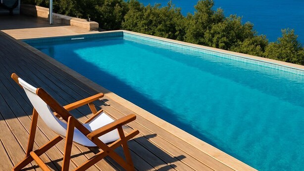 A swimming pool with a wooden deck and a lounge chair, overlooking a mountainous landscape and a body of water. - Meganisi Villa Armonia - Private Pool Oasis (Vathi)