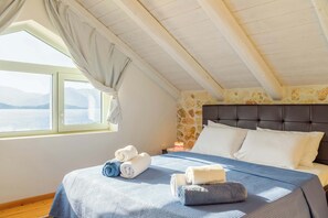 Une chambre avec un lit, des serviettes, une table de chevet et une vue sur la mer.