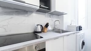 A modern kitchen with a stainless steel sink, a kettle, a knife block, and a microwave. - Italianway - Ozieri 7 (Milan)