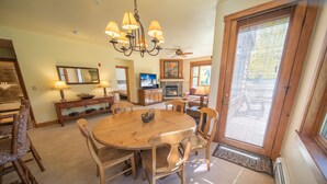 A spacious dining area with a wooden table and chairs, a chandelier, and a fireplace. - Cozy Townhome in River Run, Walk to Shops, Dining! (Keystone)