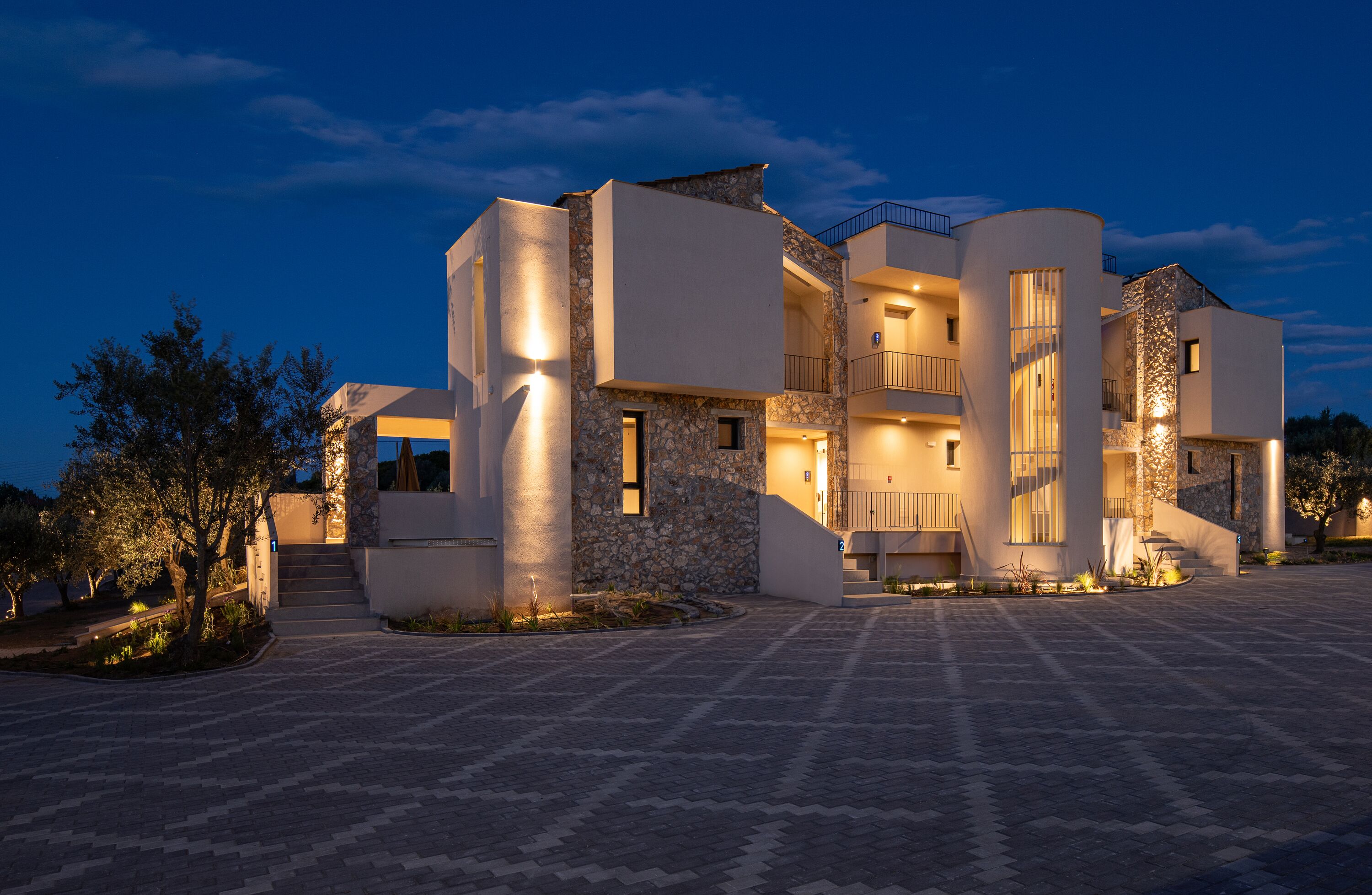 Un edificio moderno de varios pisos con fachada de piedra, varios balcones y un amplio espacio de entrada.