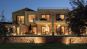 A modern two-story house with a stone facade, large windows, and outdoor seating.