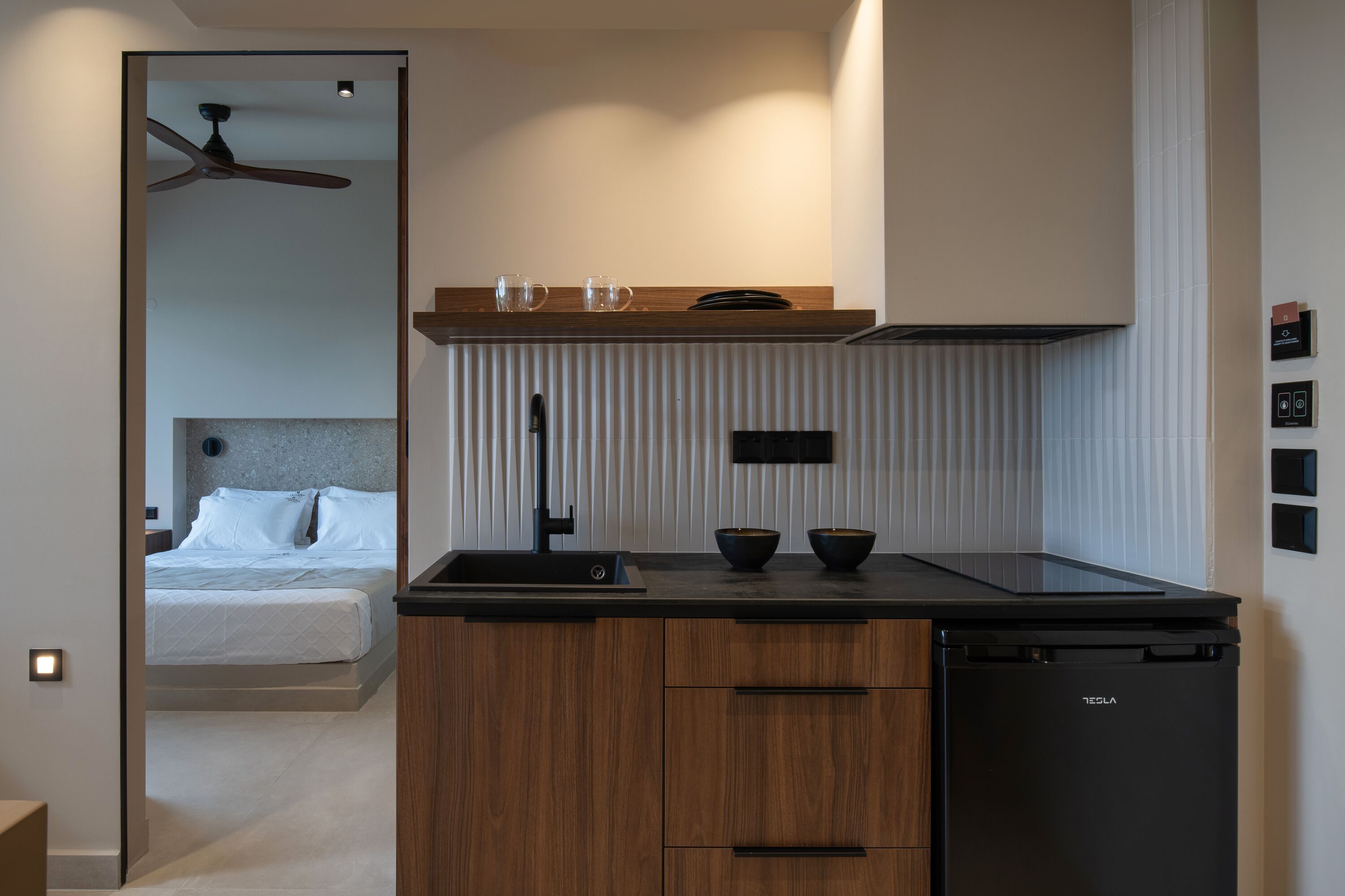 Una cocina moderna con armarios de madera, un lavavajillas negro y una encimera con dos boles y dos vasos.