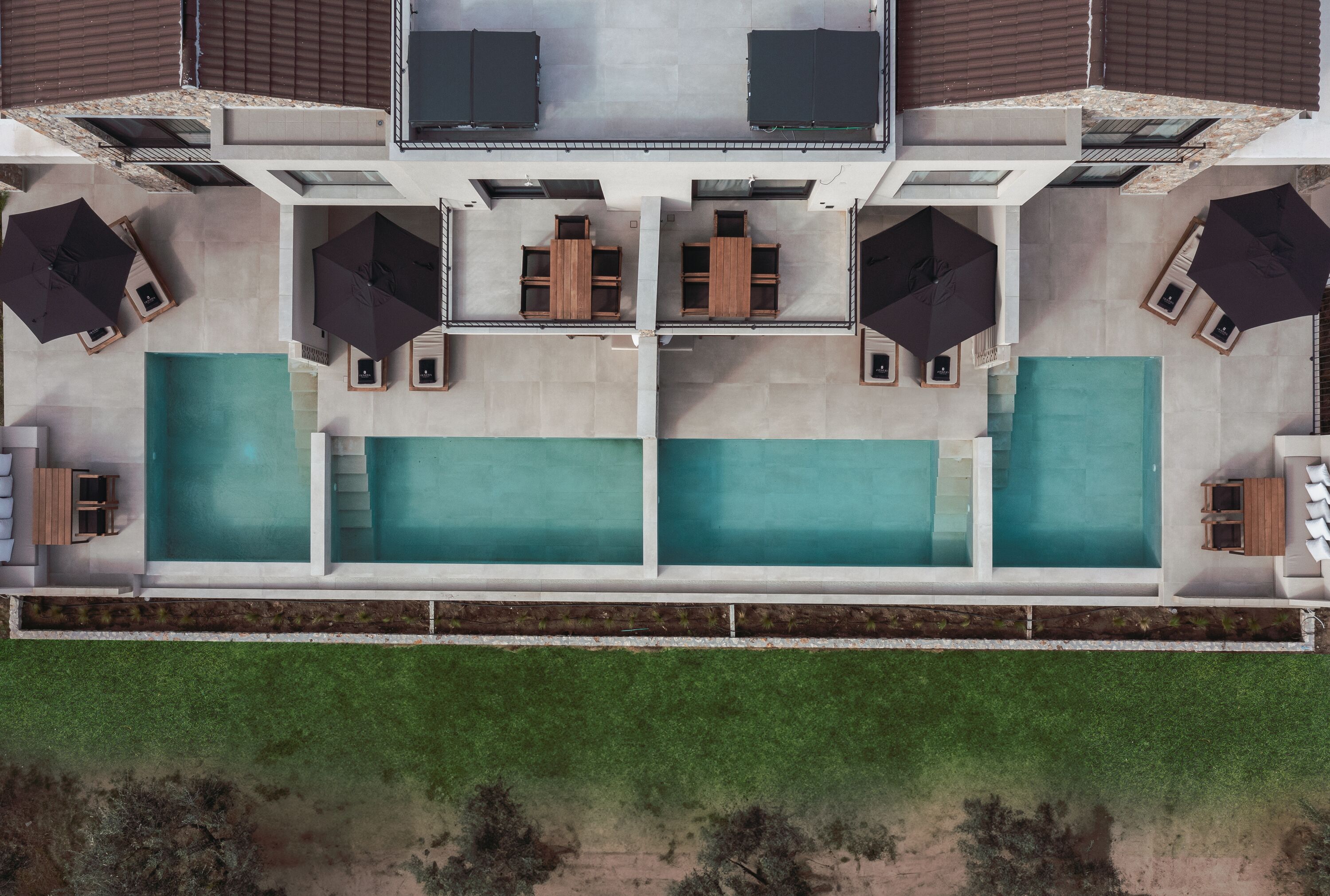 Ein modernes Gebäude mit Dachterrasse, zwei Schwimmbecken und Außenbereich-Sitzgelegenheiten.