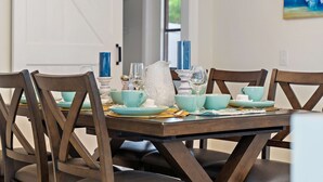 A dining table set with teal and white dishes, blue candles, and a white pitcher. - Coastal Breeze on 66th Avenue (Pinellas Park)