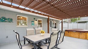 A covered patio with a table and chairs, a wooden bench, and a decorative wall piece. - Coastal Breeze on 66th Avenue (Pinellas Park)