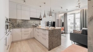 A modern kitchen with granite countertops, white cabinets, and pendant lighting. - RentPlanet - Apartament Długa (Wroclaw)