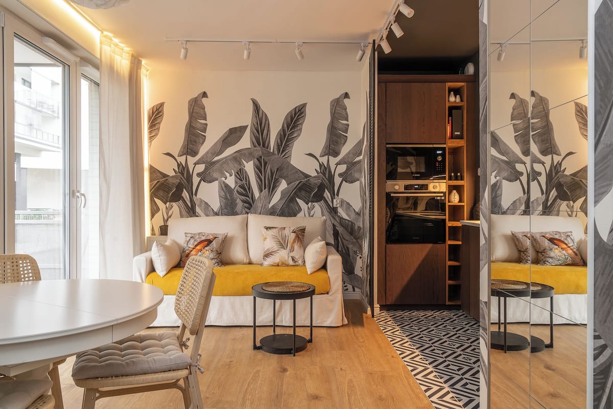 A modern living room with a sofa, a dining table, and a kitchen area.