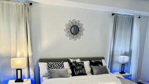 Ein Hotelzimmer mit einem Bett, zwei Nachttischen, einem Deckenventilator und einer Wanduhr.