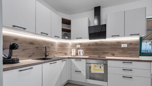 Une cuisine moderne avec des meubles blancs, un pare-feu en bois et un four encastré.