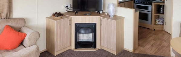 A compact living space with a sofa, a television, a fireplace, and a kitchen area with an oven and cabinets.