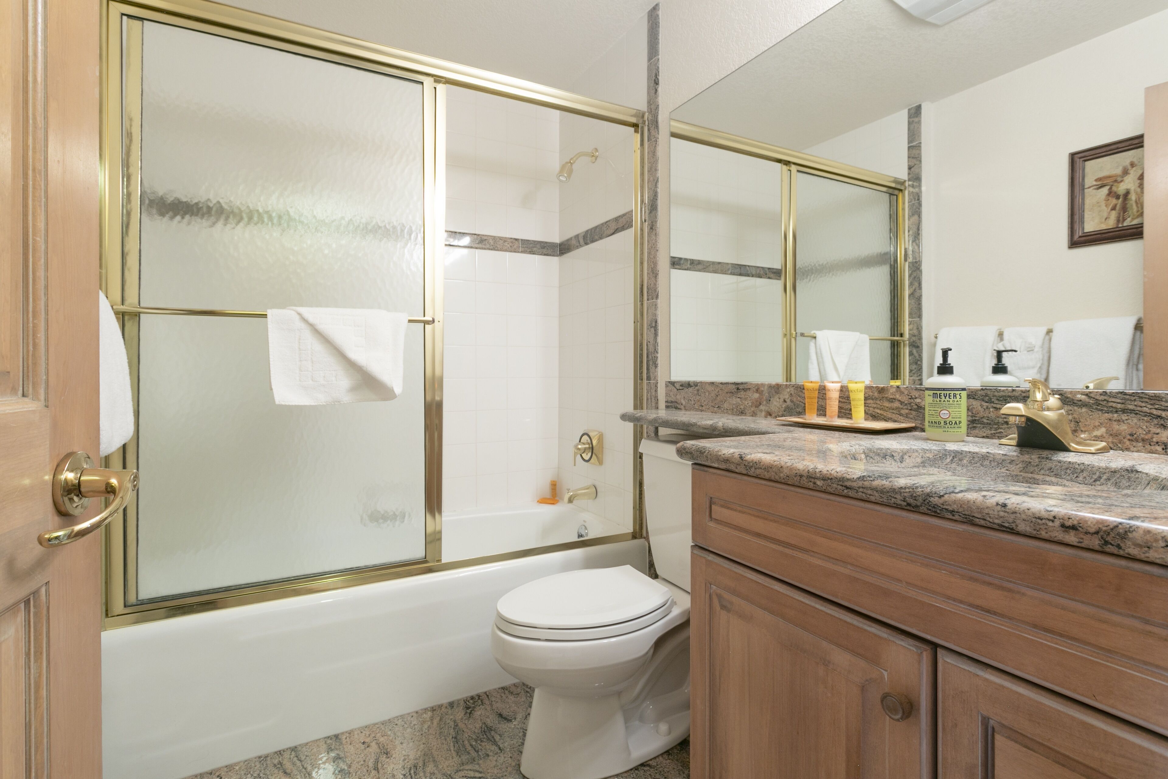 Une salle de bain équipée d’une douche, de toilettes, d’un meuble-lavabo et d’un miroir.
