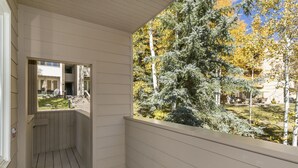 Eine Holzterrasse mit Blick auf einen Garten und Bäume.