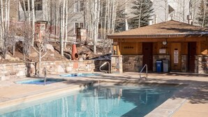 Un área de piscina con una cabaña de madera y paredes de piedra.