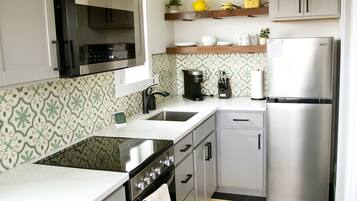 A compact kitchen with a stove, oven, microwave, and refrigerator.