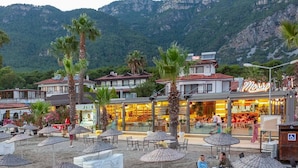 A beachside restaurant with outdoor seating and a view of the mountains. - Mosso Boutique Hotel (Ula)
