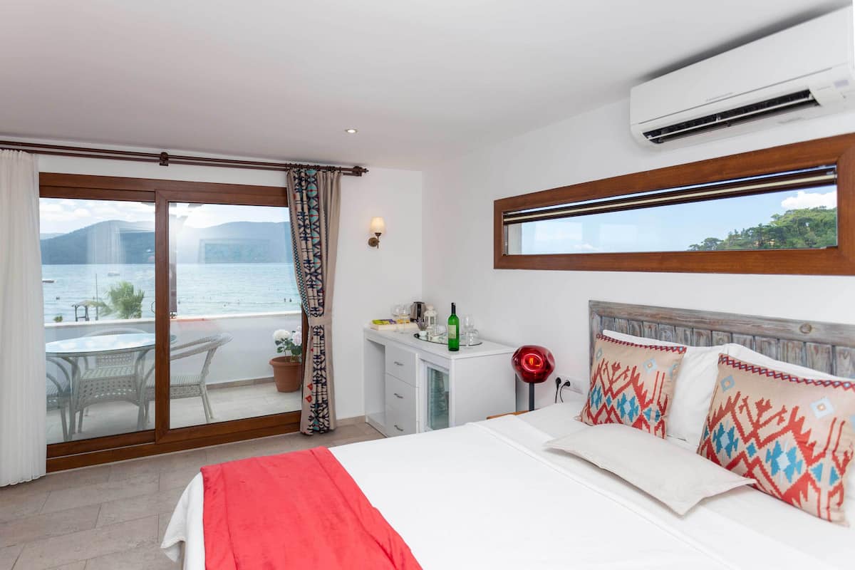 Ett hotellrum med en säng, ett skrivbord, en stol och utsikt över havet.