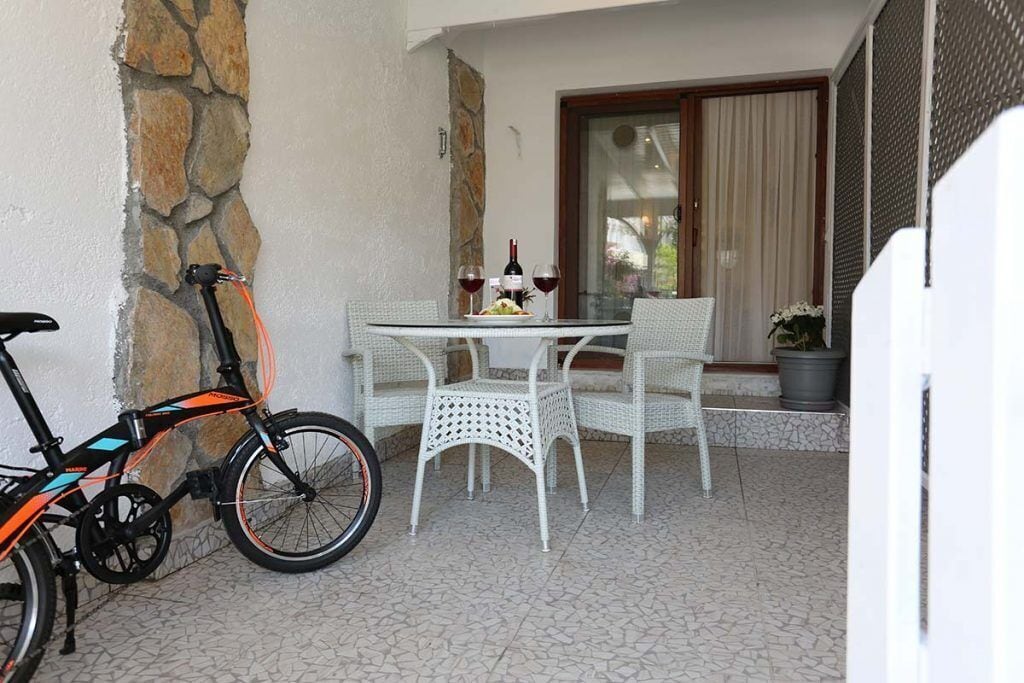 A patio with a table and chairs, a bicycle, and a stone wall.