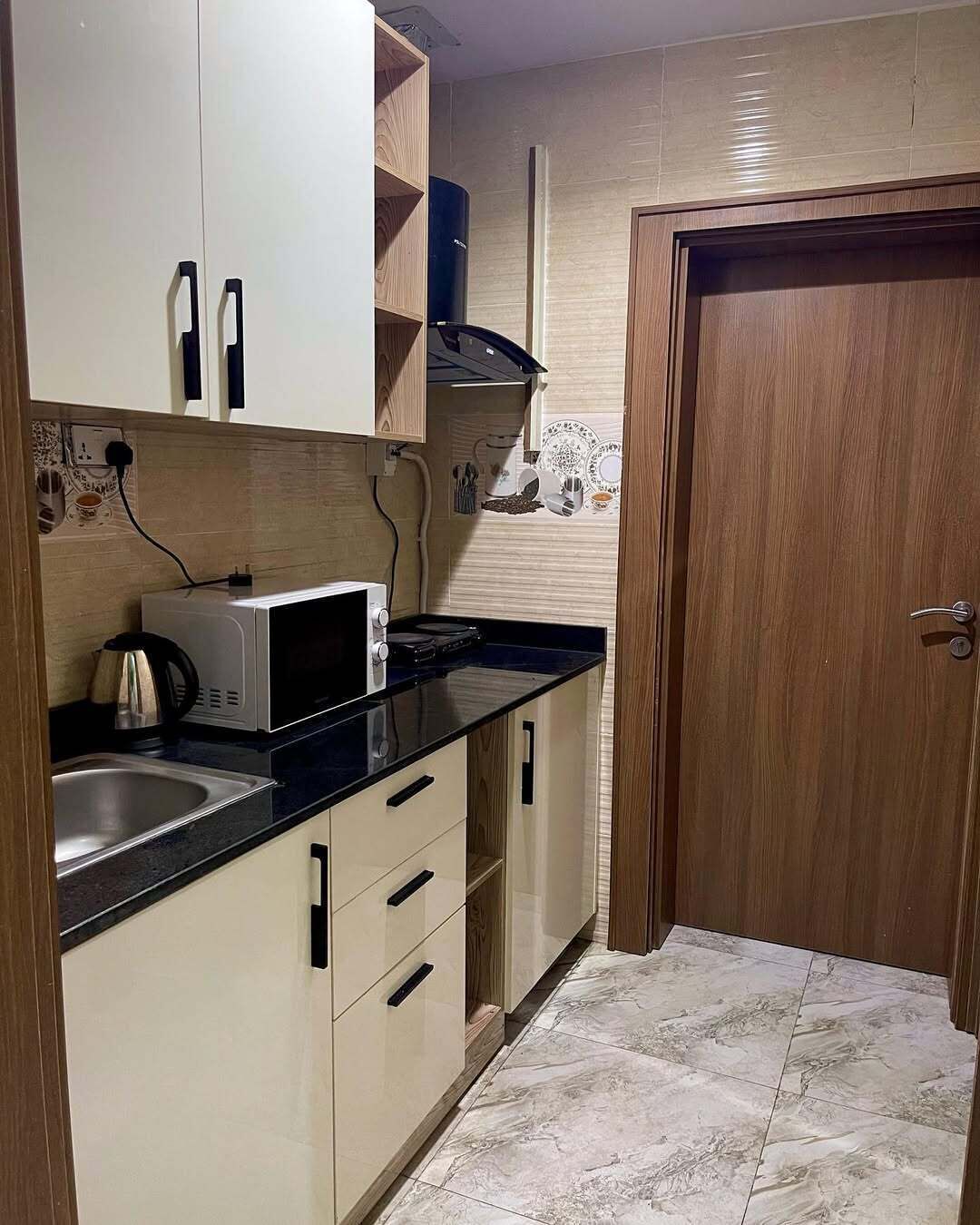A compact kitchen with a microwave, sink, and wooden cabinets.