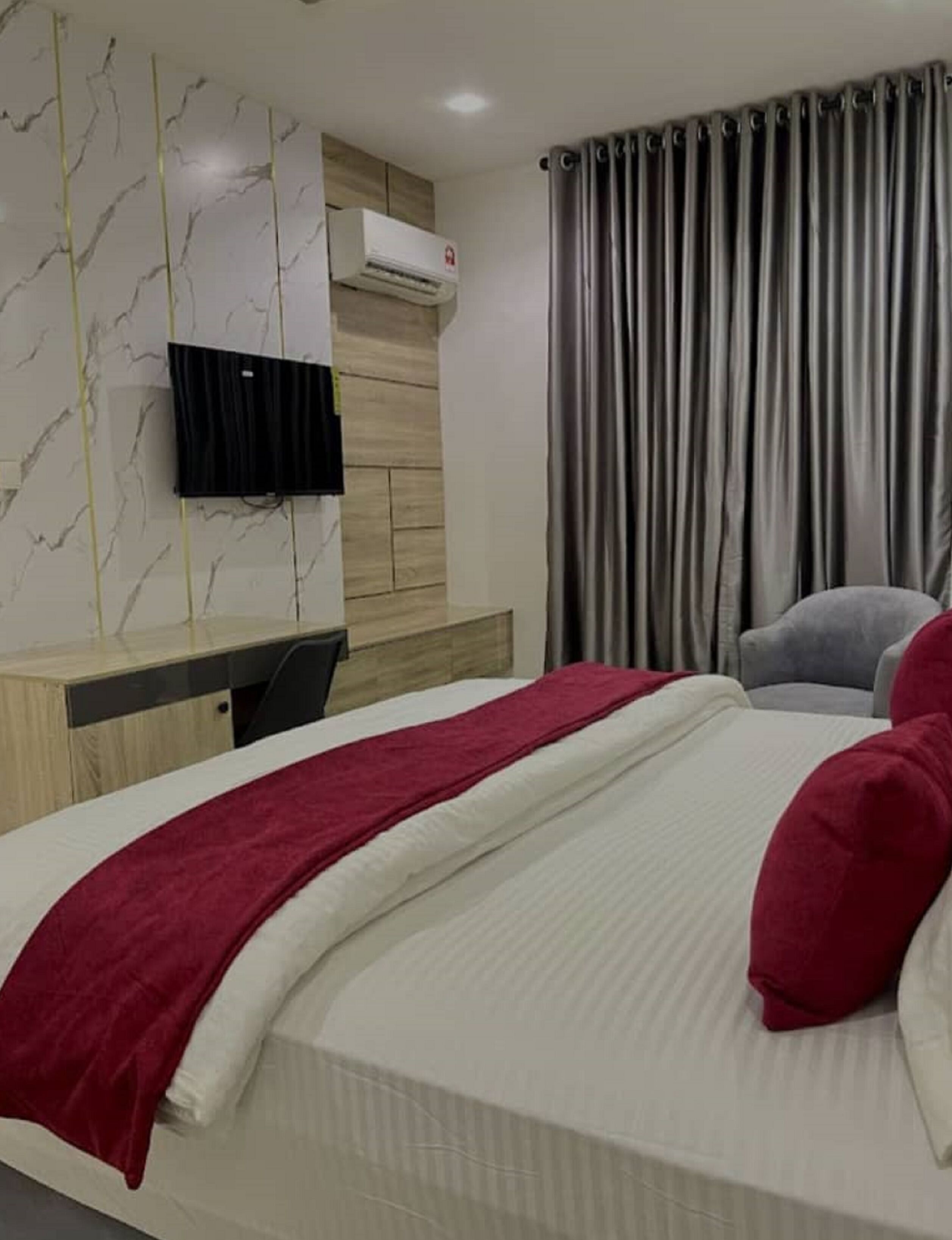 Ein Hotelzimmer mit Bett, Wandfernseher, Schreibtisch und Stuhl.