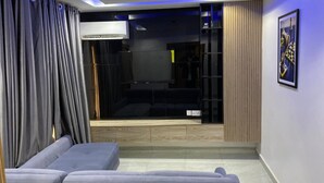 A modern living room with a sofa, a sliding glass door leading to a balcony, and a framed picture on the wall.