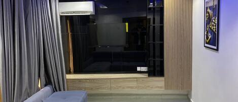 Una sala moderna con un sofá, un ventanal corredera que da a un balcón y un cuadro en la pared.
