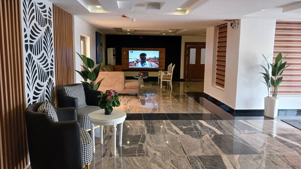 A modern lobby with a marble floor, a television, and seating areas.