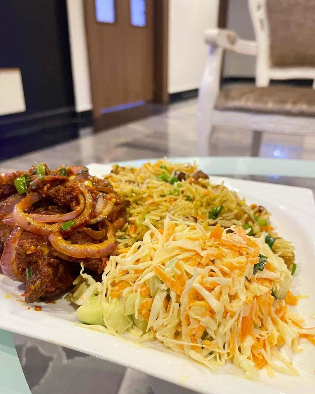 A plate of food with rice, onions, and a coleslaw salad.