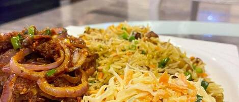 A plate of food with rice, onions, and a coleslaw salad.
